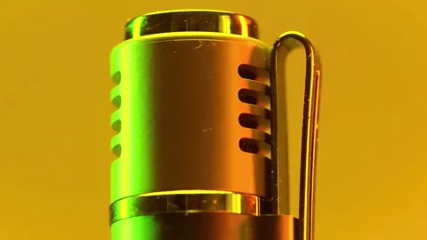 A matalistic microphone top rotating slowly under vibrant green and yellow light Stock-Footage 341801722