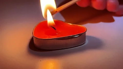 A match ignites a small candle shaped like a red heart. Video mp4, 4K qualit Stock Footage 266050186