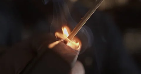 Match ignition on a matchbox held by the hand of a caucasian man Video stock 201303931