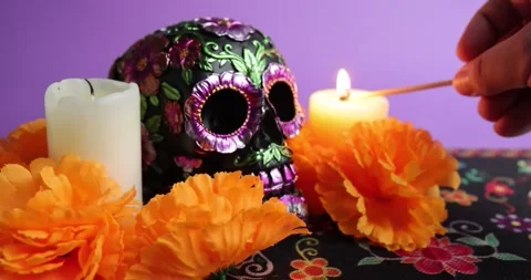 A match illuminates candles around a skull adorned with marigolds Stock Footage 281829705