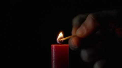 Match lighting single candle isolated on black background. Wick lights up flame Stock Footage 332502348
