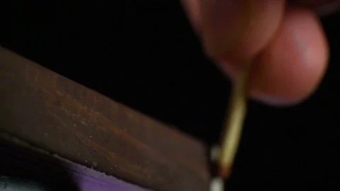 The match moves on the side of the matchbox and lights up. Close-up. Shallow Stockbeeldmateriaal 83998625