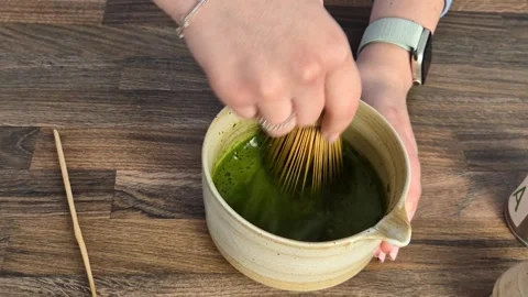Matcha coffee making process. Mixing green matcha powder with a whisk in a wo Stock Footage 304740938