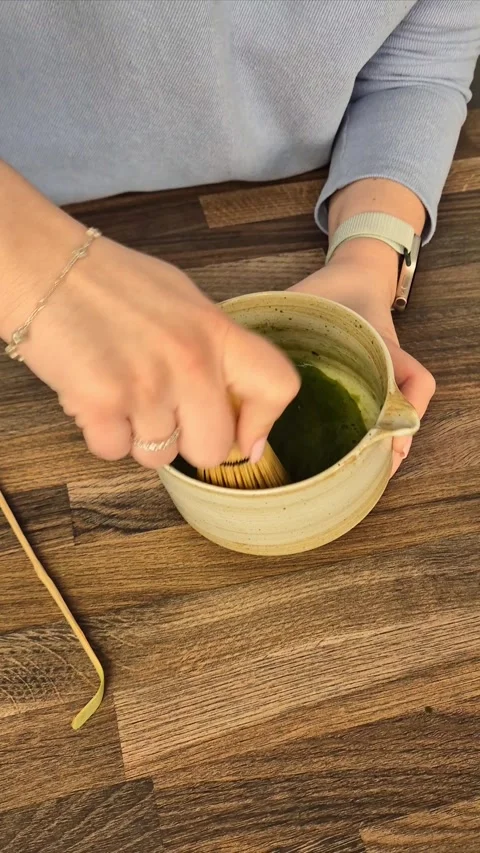 Matcha coffee making process. Mixing green matcha powder with a whisk in a wo Stock Footage 304740940
