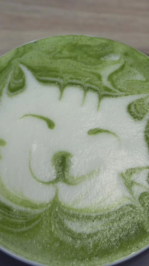 Matcha green tea latte art with smiling cat face design in white foam. Stock Footage 339638980