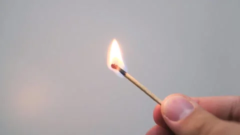 Matchstick burning, casting warm glowing light against stark white background Stock Footage 296847471