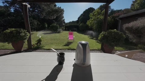 Mate tea ceremony set on a table in a sunny garden with sprinklers watering.. Stock Footage 328765285
