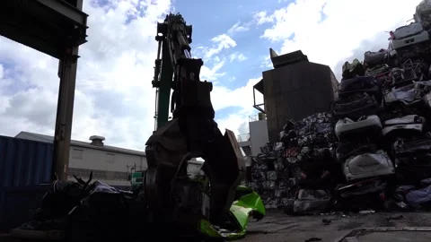 Material handler with an orange peel grab lifting crushed car bodies from a Vídeo Stock 340565779