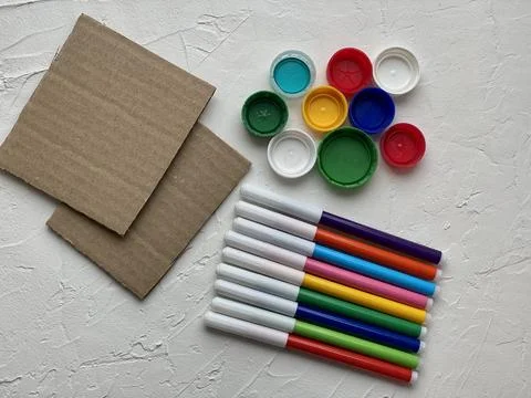 The material for kid creativity is cardboard markers and plastic lids. Stock Photos