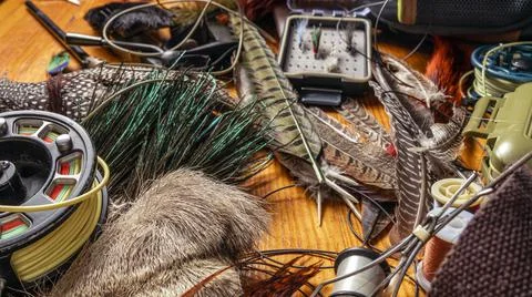 Materials and tools for tying lures on a wooden table. Fly Fishing Still Life. Stock Photos