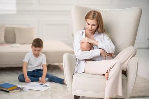 Maternal connection with the child. Behind the son draws a card for mom at home. Stock Photos