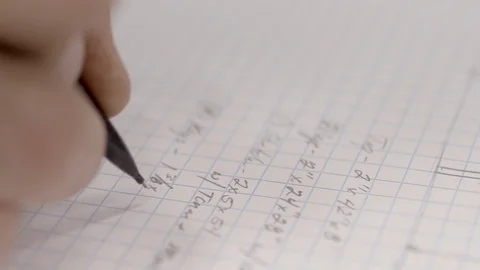 A math equation with numbers and fractions is written out in a notebook, Stock Footage 124159166