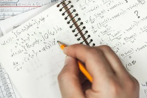 Math formulas are written in pencil in a notebook holding man in Foto stock