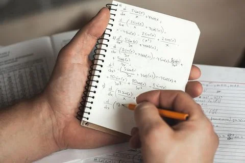 Math formulas are written in pencil in a notebook holding man in Stock Photos