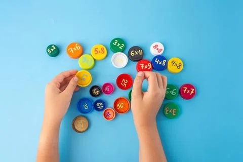 Math learning game with child hands sorting colorful caps with multiplicati.. Stock Photos