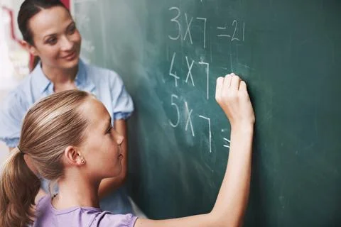Math, teacher and student writing on chalkboard in classroom for solving number Stock Photos