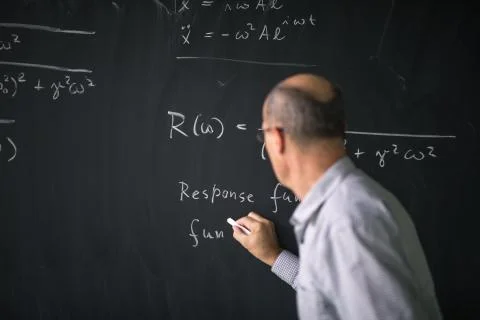 Math teacher drawing   fuction graph on a blackboard during mathclass  Stock Photos