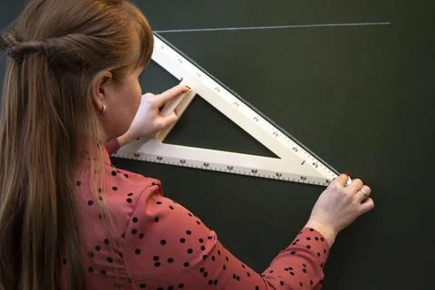 A math teacher explains the lesson to students near the blackboard. Stock Photos