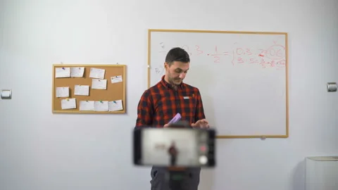 Math teacher explains online lesson to students using marker and white board Stock Footage 139864095