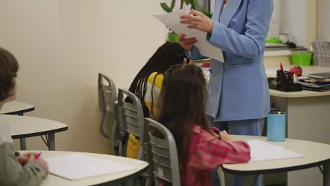 Math teacher handing out graded test papers to pupils during lesson Stock Footage 335684069