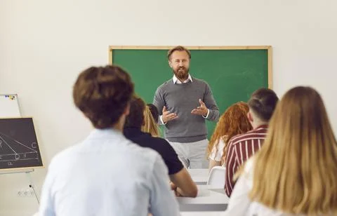 Math teacher standing in classroom and talking to group of school or college Stock Photos