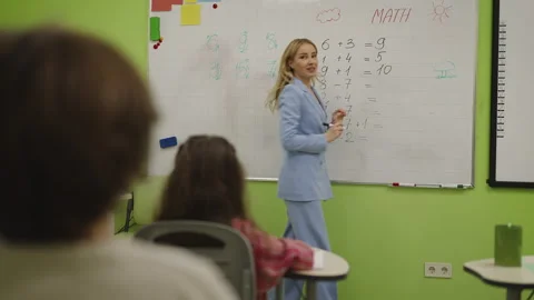 Math teacher writing equation on whiteboard during primary school lesson Stock Footage 333586307