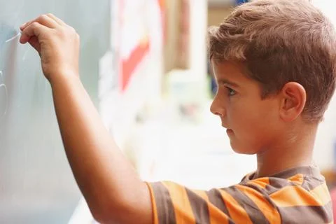 Maths genius in the making. Young boy writing the answer to a question on the Stock Photos
