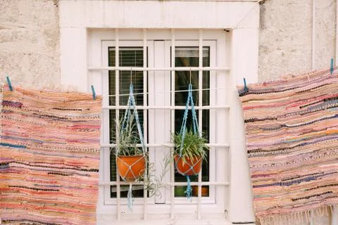The mats patchwork are dried near a white window with a grille and two flower Stock-Fotos