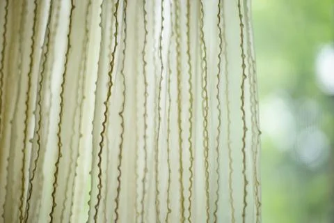 Matte tulle with vertical threads pattern. Green blurred garden in background Foto stock