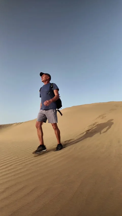 Mature active man walking alone on a desert sand dune Stock Footage 345093141