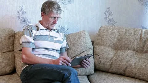 Mature adult sitting with pad on divan Stock Footage