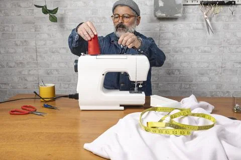 Mature adult threading sewing machine for hobby work Stock Photos
