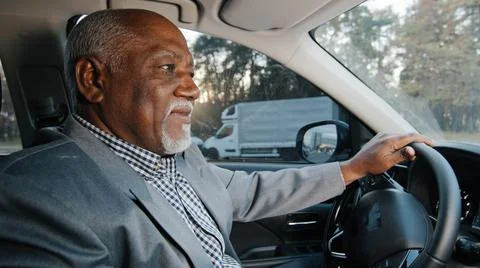 Mature african american happy male driver sits behind wheel automobile smiling Stock Photos