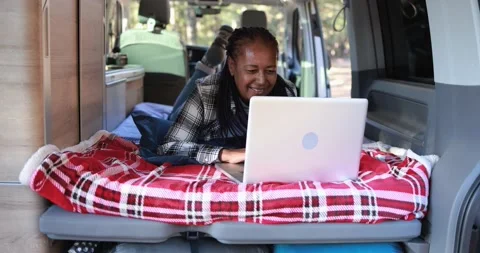 Mature african woman using computer laptop inside mini van camper Vídeos de archivo 160537916