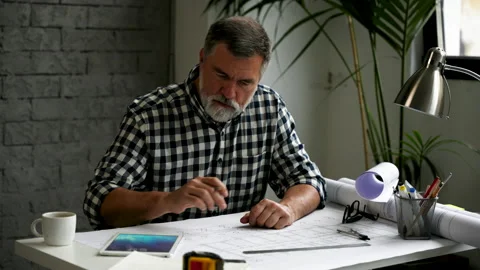 Mature architect working on blueprint, using digital tablet Video stock 231488044