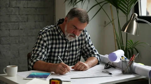 Mature architect working on blueprint, using digital tablet Stock Footage 231488425