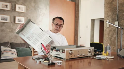 Mature Asian man disassembling audio equipment for repair, home DIY workshop. Stock Footage 347253836