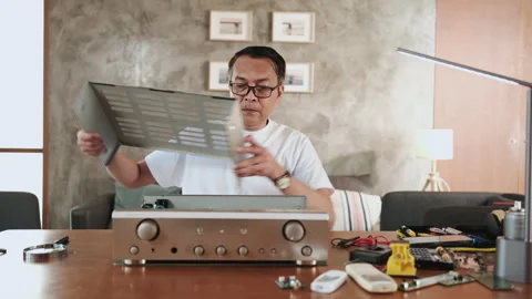 Mature Asian man disassembling audio equipment for repair, home DIY workshop. Stock Footage 348052205