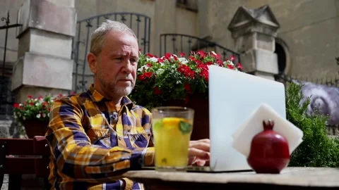 Mature attractive bearded man using laptop outside enjoying networking online on 스톡 동영상 163714139
