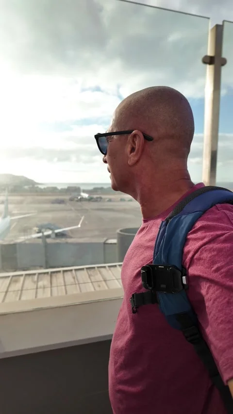 Mature bald man looking at the runway from the airport window Stock Footage 345362368