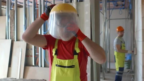Mature builder putting on plastic face mask on construction site Stock Footage 133635033