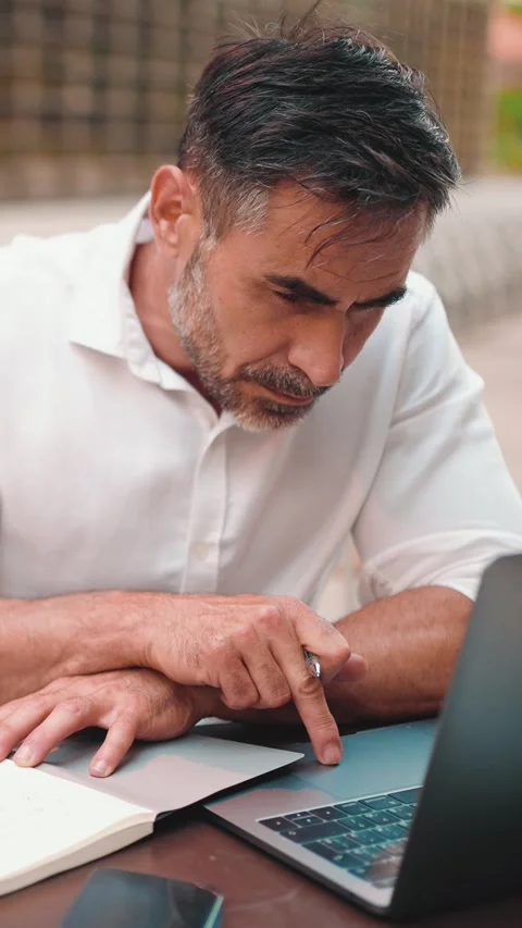 Mature businessman with beard, user on laptop pc computer and make notes sit at Stock Footage 227003653