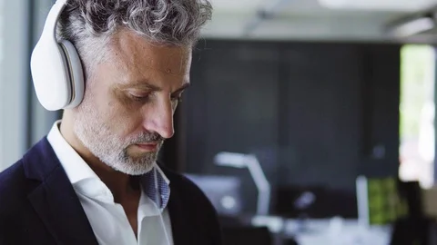 Mature businessman with earphones and smartphone. Stock Footage