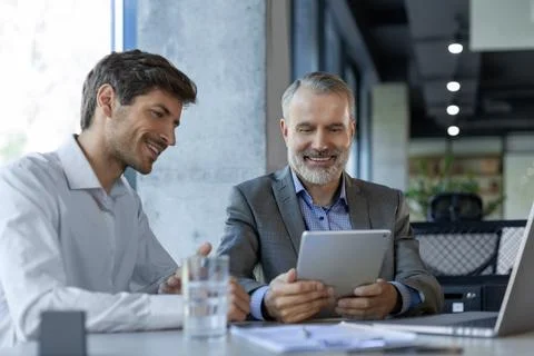 Mature businessman using a digital tablet to discuss information with a young Stock Photos