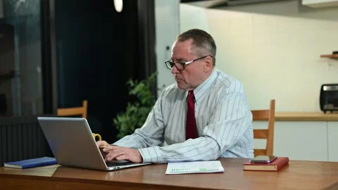 Mature Businessman using laptop while sitting at home. man sitting in kitch.. Stock Footage 313460716