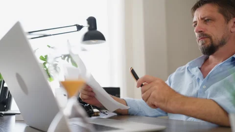 Mature businessman working remotely, reading a document at his home office .. Stock Footage 341748452