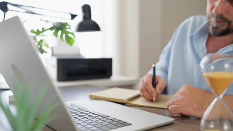 Mature businessman writing notes in a notebook while working from home with.. Stock Footage 341625219