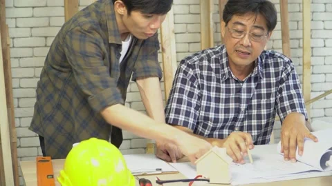 Mature carpenter is teaching a young man apprentice. Video stock 144712296