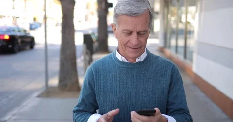 Mature caucasian man walking street texting on cell phone typing message Stock Footage