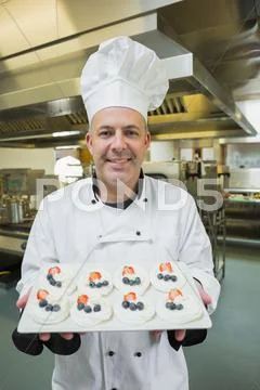 Mature chef presenting proudly plate of meringues Stock Photos
